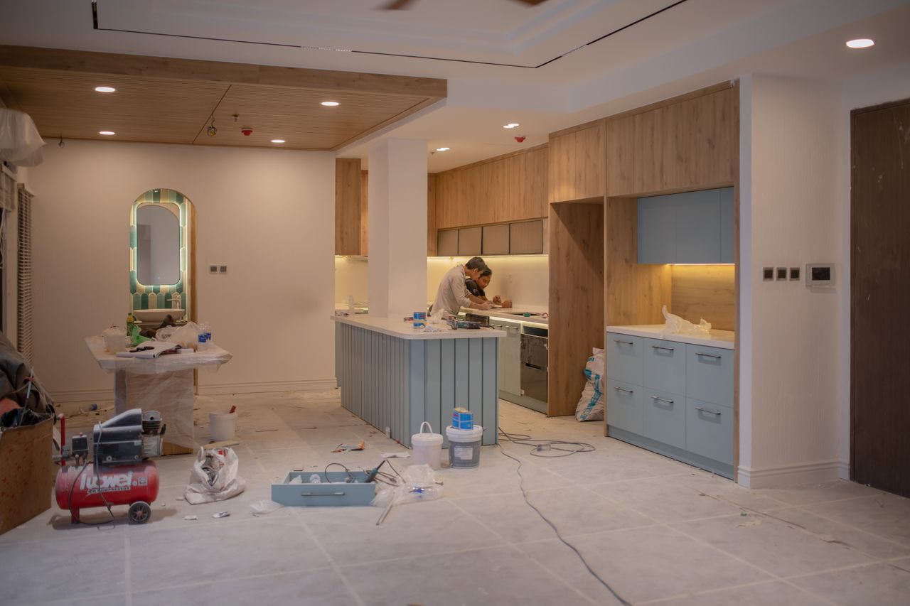 Offerings A modern kitchen undergoing renovation, featuring a worker, tools, and materials.